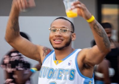 Man with a drink and hands in the air dancing at an Okinawa pool party